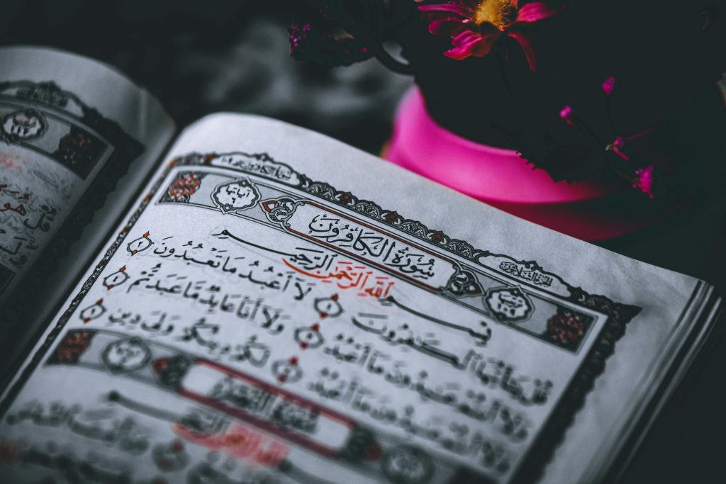 Elegant close-up of an open Quran page with vibrant pink flowers accentuating the sacred text.